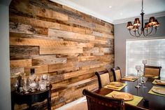 a dining room table with place settings on it and wooden wall in the back ground