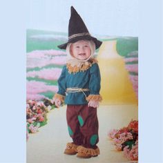 a young child dressed in a scarecrow outfit and hat, standing on a path