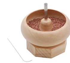 a wooden bowl filled with lots of red beads next to a thread on a white background