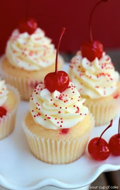 several cupcakes with white frosting and red sprinkles on top