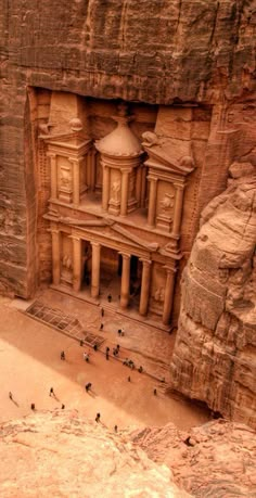 people are standing in front of an ancient building carved into the side of a cliff