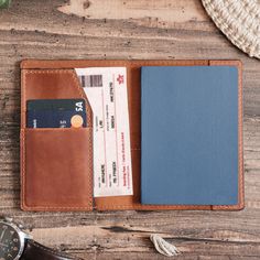 a wallet and passport are sitting next to each other on a wooden table with a watch