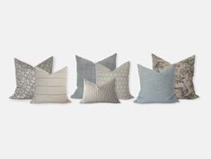 four different pillows lined up in a row on a white background, one is grey and the other is blue