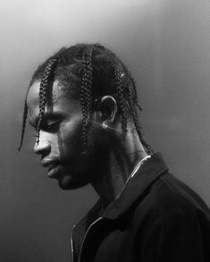 a man with dreadlocks standing in front of a wall