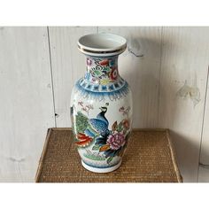 an ornate vase with flowers painted on it sitting on a mat in front of a wooden wall