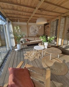 an outdoor living room with wooden floors and furniture on the floor, along with potted plants