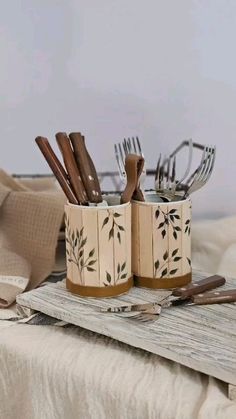 two mugs filled with forks and spoons sitting on top of a bed