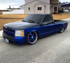 a blue pick up truck parked in front of a house on the side of the road