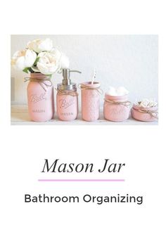 mason jar bathroom organizing with pink jars and white flowers in the center, on a table