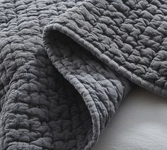 a close up view of a bed with a gray blanket on top of the bed