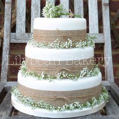 a three tiered wedding cake decorated with baby's breath flowers and burlap