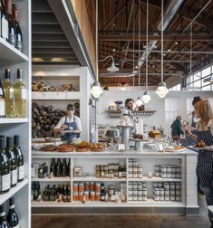 two people standing in front of a counter filled with food