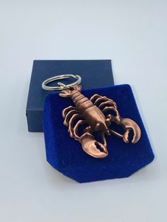 a scorpion keychain sitting on top of a blue velvet box