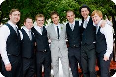 a group of men standing next to each other in front of a wooden bench wearing suits and ties