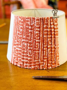 a lamp shade sitting on top of a wooden table next to a pair of scissors