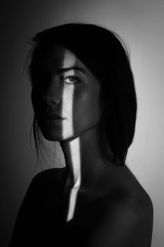 a black and white photo of a woman's face with her shadow on the wall