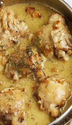 a pan filled with chicken and gravy on top of a table next to silverware