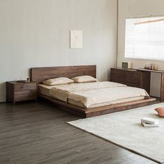 a bed sitting in a bedroom next to a wooden dresser and lamp on top of a hard wood floor