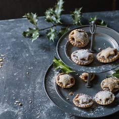 several small pastries are on a plate with holly leaves and sprigs in the background