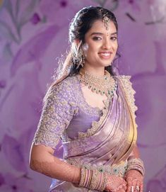 a woman in a purple sari with jewelry on her neck and hands behind her back