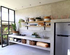 a kitchen with a refrigerator freezer sitting next to a window filled with potted plants