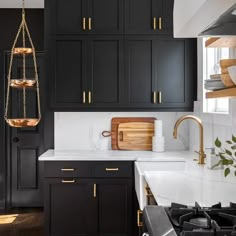 a kitchen with black cabinets and white counter tops, gold accents on the handles and pulls