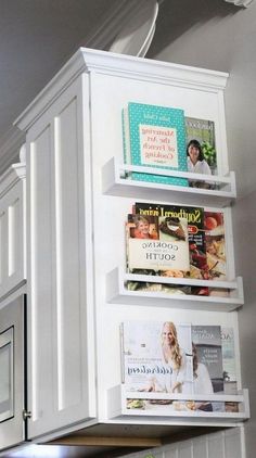 the kitchen cabinets are all white and have books on them, along with magnets