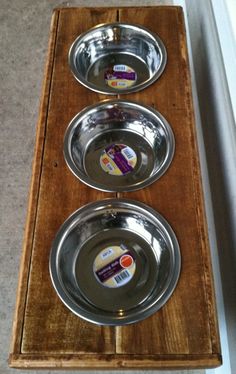 three metal bowls sitting on top of a wooden stand