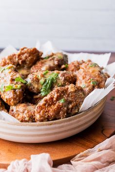 some meatballs are sitting in a bowl on a wooden table with white napkins