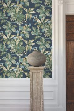 a vase sitting on top of a pedestal in front of a wallpapered background