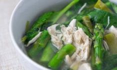 a white bowl filled with green vegetables and meats on top of a cloth covered table