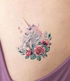 the back of a woman's stomach with an unicorn and flowers tattoo on it