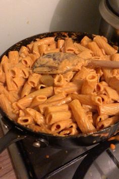 a pan filled with pasta on top of a stove next to an oven burner