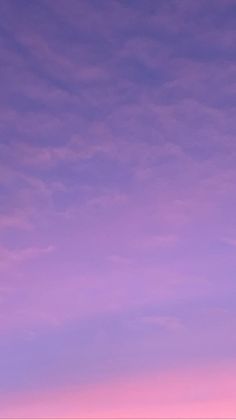 two people standing on the beach with surfboards under a purple sky at sunset or dawn