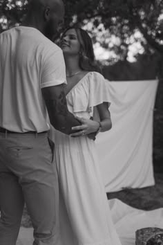 a man and woman standing next to each other in front of a white cloth covered backdrop