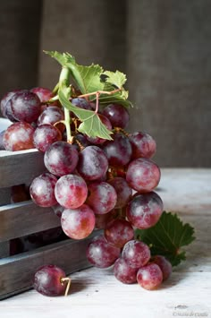 a bunch of grapes sitting on top of a wooden crate