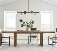 a dining room table with two chairs and a potted plant