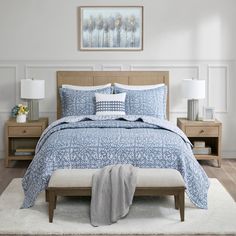 a bed with blue and white comforter in a bedroom next to two nightstands