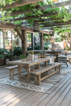 an outdoor dining area with wooden tables and benches under a pergolated roof, surrounded by potted plants