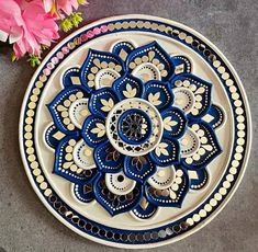 a blue and white plate sitting on top of a table with pink flowers in the background