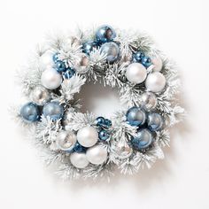 a christmas wreath with ornaments hanging from it's sides on a white wall background