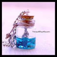 a glass jar filled with blue and white beads on a table next to a chain