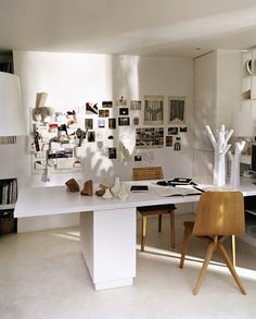 a white table and chairs in a room with pictures on the wall behind it,