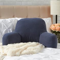 a blue chair sitting on top of a bed next to a vase with flowers in it