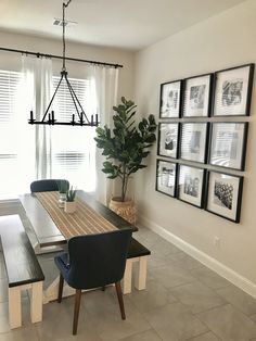 a dining room table and chairs with pictures on the wall above it, along with a potted plant