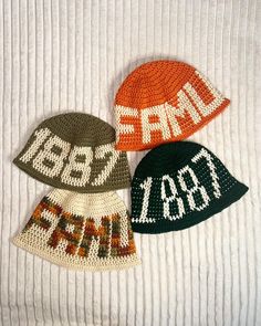 three crocheted hats sitting on top of a white blanket next to each other