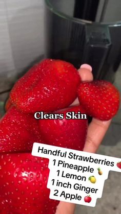 two strawberries are being held in front of a glass container with labels on them