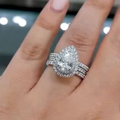 a woman's hand with a diamond ring on top of her finger and the other hand holding an engagement ring