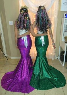 two women in mermaid dresses standing next to each other with their hands on their hips