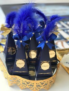 blue feathers are placed on top of black boxes with gold trimmings and ribbons